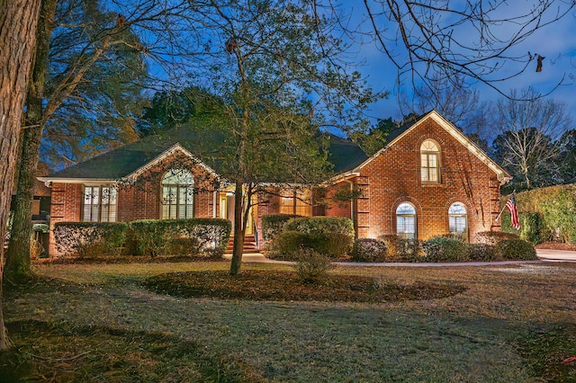 view of front facade with brick siding and a front yard