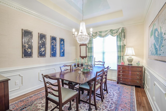 dining space featuring a tray ceiling, wood finished floors, and wainscoting