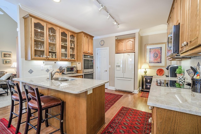 kitchen featuring backsplash, crown molding, appliances with stainless steel finishes, a peninsula, and a sink