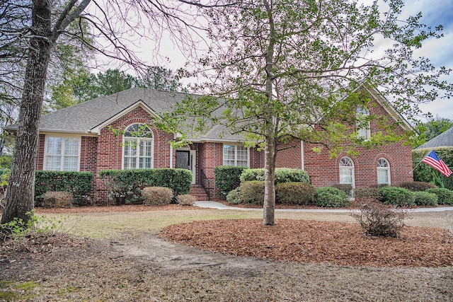 view of front of house featuring brick siding and roof with shingles