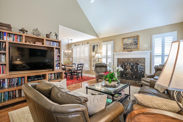 living room with a wealth of natural light, a chandelier, wood finished floors, and a high end fireplace