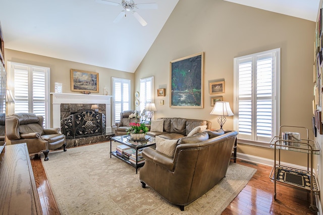 living area featuring hardwood / wood-style floors, baseboards, visible vents, high vaulted ceiling, and a high end fireplace