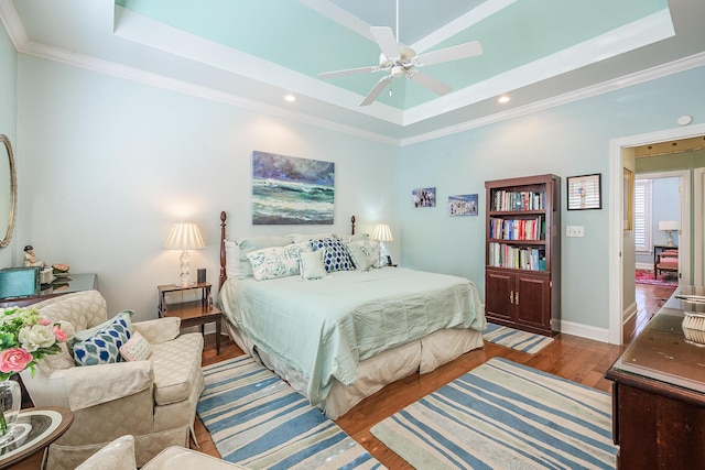 bedroom featuring ornamental molding, a tray ceiling, and wood finished floors