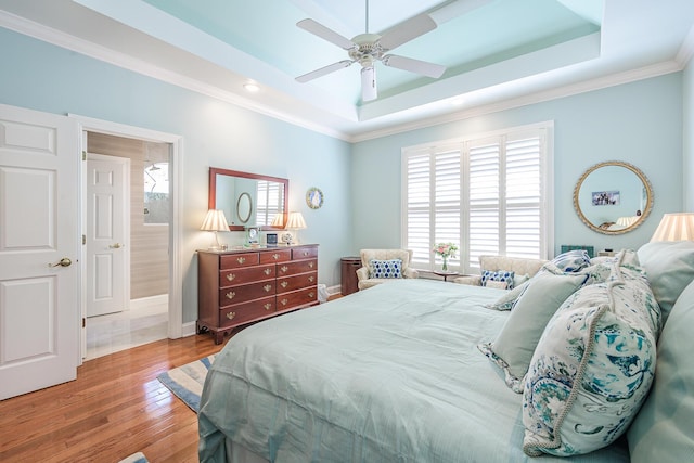 bedroom featuring multiple windows, crown molding, a tray ceiling, and wood finished floors