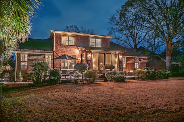 back of house at twilight featuring brick siding