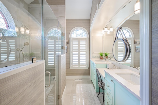 bathroom with tile patterned flooring, double vanity, tiled shower, and a sink