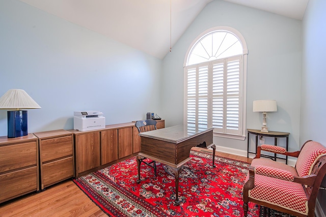 home office featuring light wood-style flooring, baseboards, and vaulted ceiling