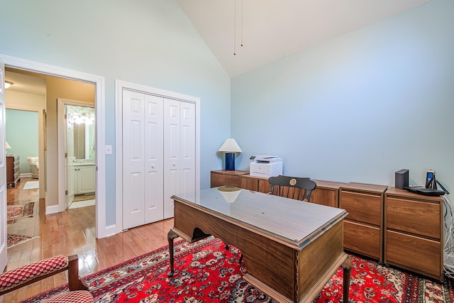 office space featuring baseboards, light wood-style floors, and high vaulted ceiling