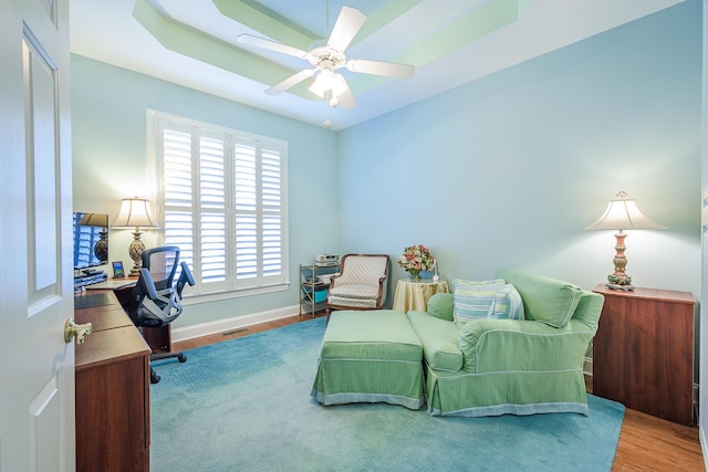 home office with a ceiling fan, wood finished floors, visible vents, and baseboards