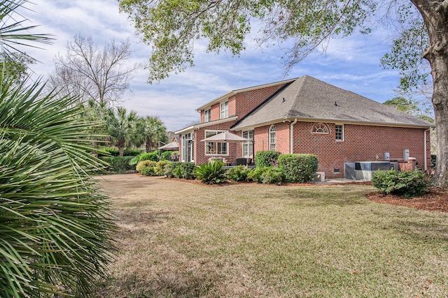 view of side of home featuring brick siding, central air condition unit, a shingled roof, and a yard