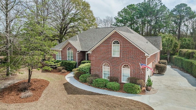 traditional-style home with brick siding, roof with shingles, and driveway