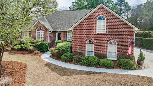 view of front of home featuring brick siding and a shingled roof