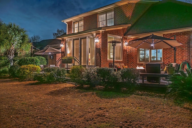 back of house at night with brick siding and a patio area