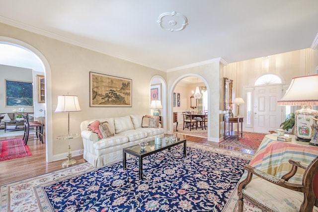 living room featuring arched walkways, wood finished floors, and ornamental molding