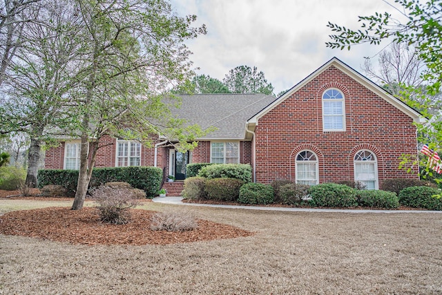 view of front facade with brick siding and a shingled roof