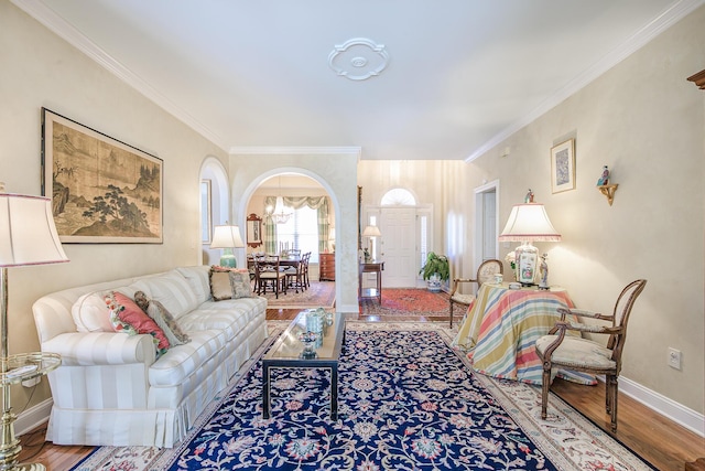 living room featuring arched walkways, ornamental molding, baseboards, and wood finished floors