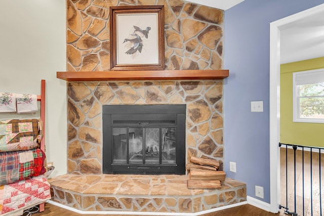 details with wood finished floors and a stone fireplace