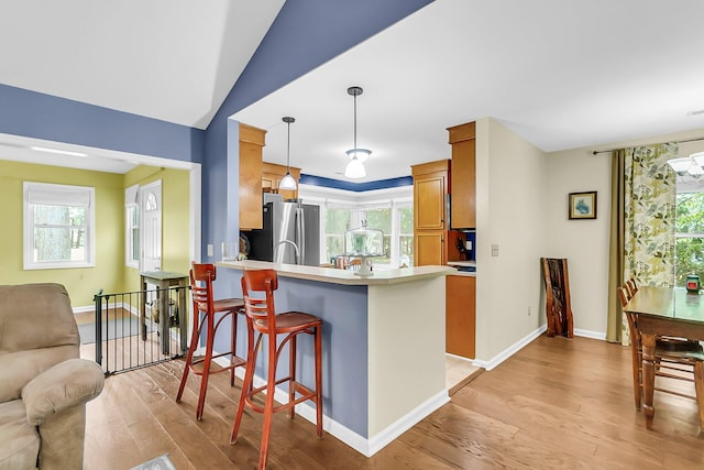 kitchen featuring a peninsula, freestanding refrigerator, light wood-style flooring, open floor plan, and light countertops