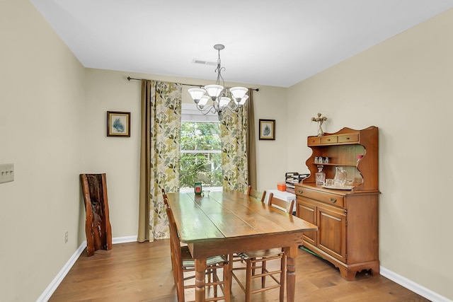 dining space featuring baseboards, an inviting chandelier, visible vents, and light wood-style flooring