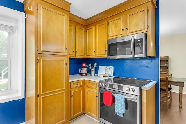 kitchen featuring light countertops, stainless steel appliances, and brown cabinetry