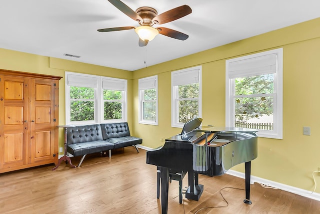 living area featuring baseboards, a ceiling fan, visible vents, and light wood-style floors
