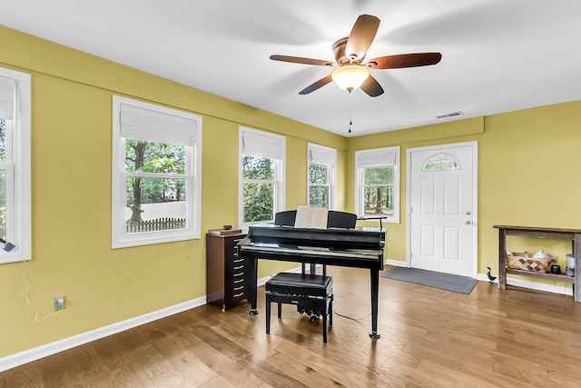 living area with ceiling fan, visible vents, baseboards, and a healthy amount of sunlight