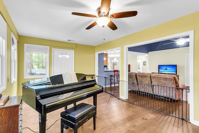 living area with an upstairs landing, a ceiling fan, visible vents, and wood finished floors