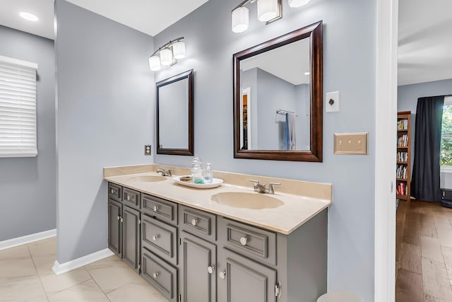 bathroom featuring a sink, double vanity, and baseboards