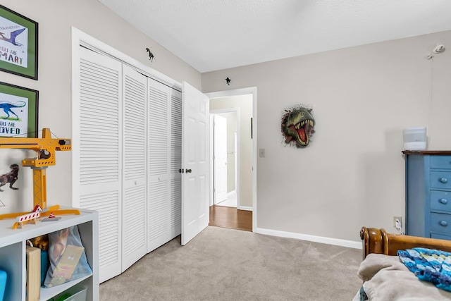 carpeted bedroom featuring a closet and baseboards
