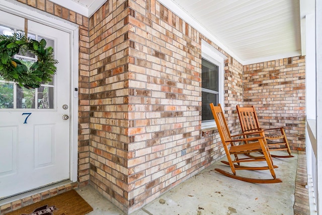 doorway to property with a porch and brick siding