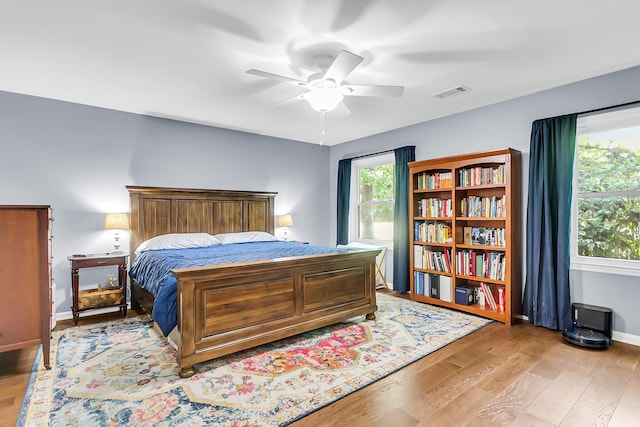 bedroom with ceiling fan, light wood-style flooring, baseboards, and visible vents