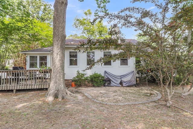 back of property with a chimney and a wooden deck