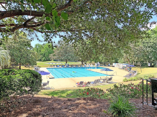 community pool with a patio area and fence