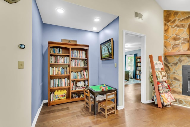 rec room with baseboards, visible vents, and wood finished floors