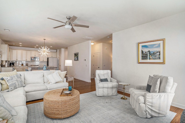 living room featuring ceiling fan with notable chandelier and light wood-type flooring