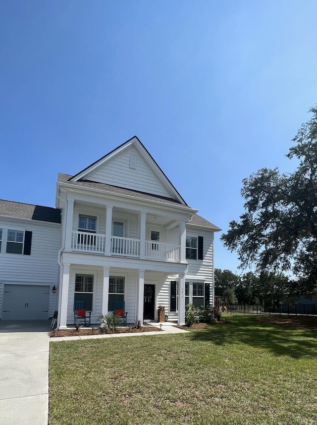 neoclassical / greek revival house featuring covered porch, an attached garage, a balcony, driveway, and a front lawn