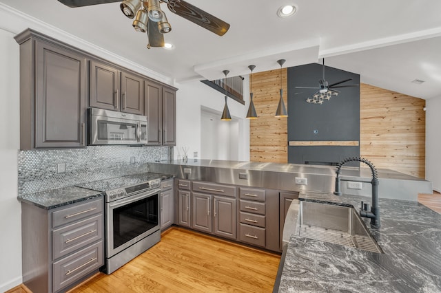 kitchen with decorative light fixtures, stainless steel appliances, wood walls, and sink