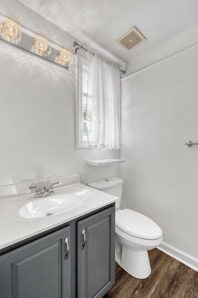 bathroom with wood-type flooring, vanity, and toilet