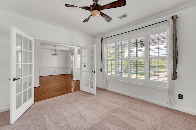 carpeted spare room with ceiling fan, french doors, and crown molding