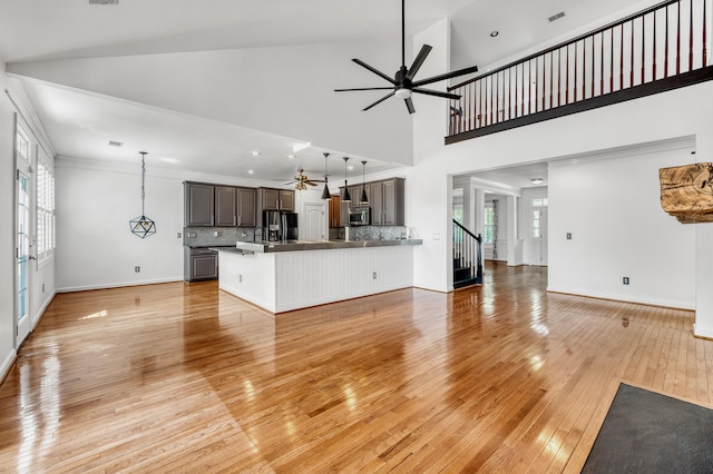 unfurnished living room with light hardwood / wood-style flooring, ceiling fan, high vaulted ceiling, and ornamental molding