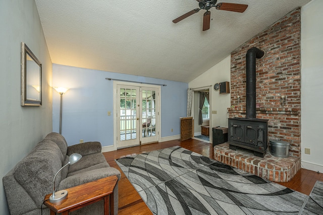 living room featuring a wood stove, wood-type flooring, vaulted ceiling, and a textured ceiling