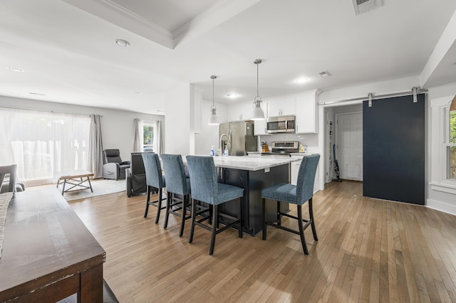 1445 Downwood Pl, Charleston, SC 29412 - kitchen with appliances with stainless steel finishes, a barn door, light wood-type flooring, a breakfast bar, and recessed lighting