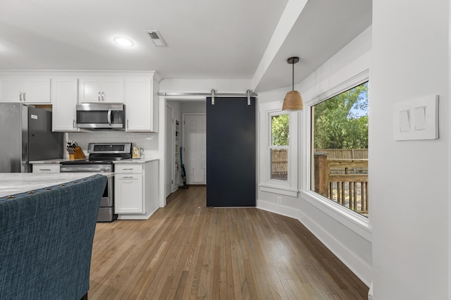 1445 Downwood Pl, Charleston, SC 29412 - kitchen featuring stainless steel appliances, a barn door, light countertops, white cabinetry, and light wood-style flooring
