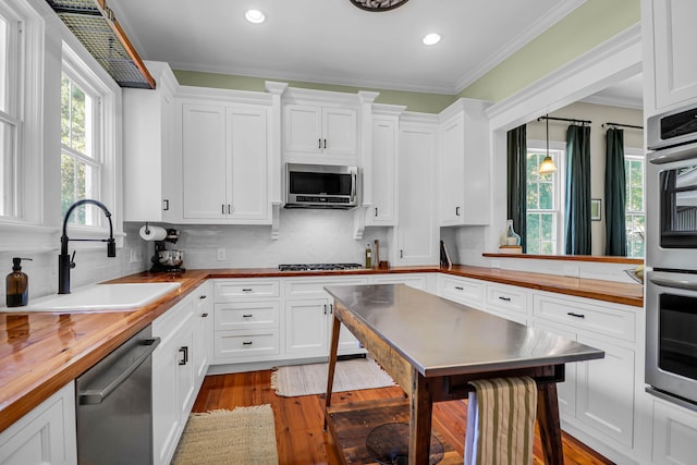 kitchen featuring pendant lighting, backsplash, light wood-type flooring, stainless steel appliances, and sink