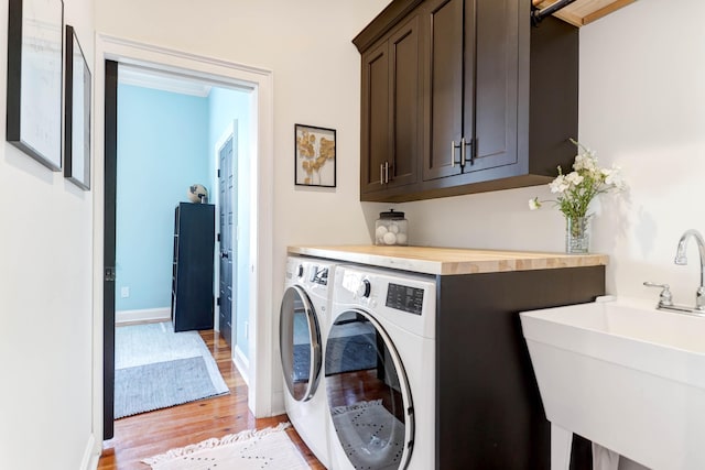 washroom featuring washer and dryer, sink, light hardwood / wood-style flooring, and cabinets