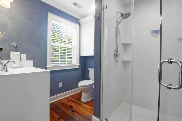 bathroom featuring hardwood / wood-style floors, crown molding, an enclosed shower, toilet, and vanity