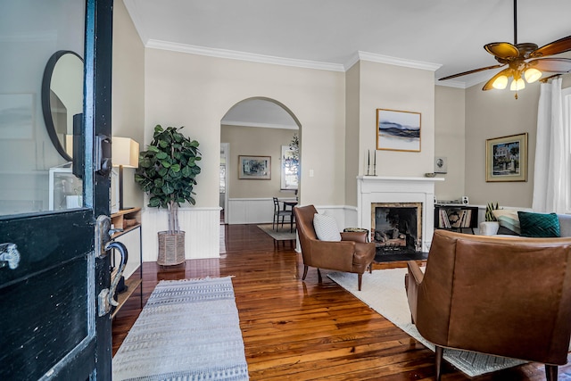 living room featuring ceiling fan, hardwood / wood-style flooring, a high end fireplace, and ornamental molding