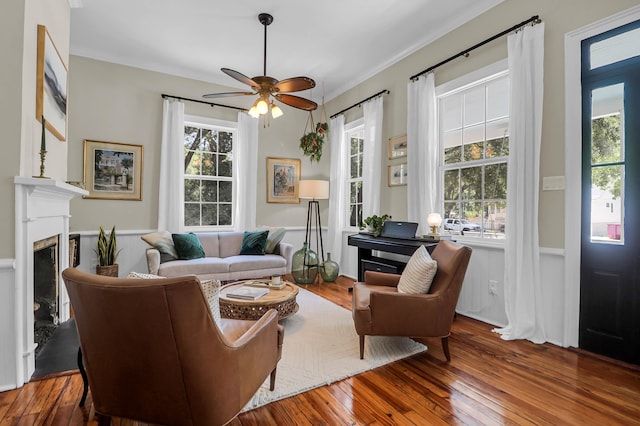 living room with a high end fireplace, ceiling fan, plenty of natural light, and hardwood / wood-style floors