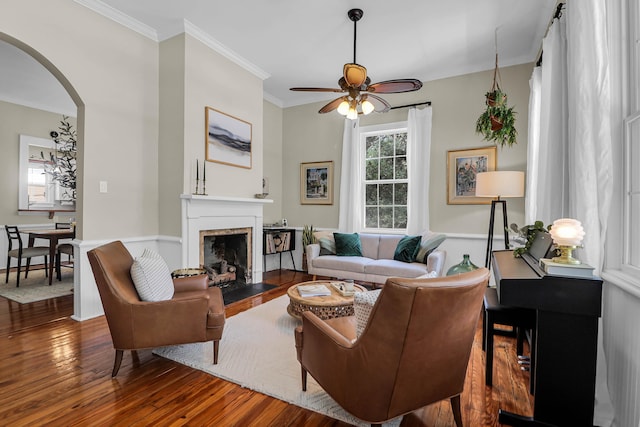 living room with a premium fireplace, ornamental molding, hardwood / wood-style floors, and ceiling fan