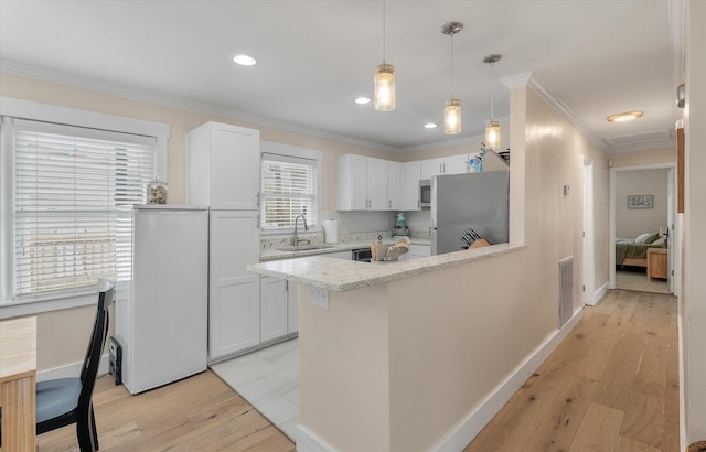 kitchen featuring a sink, appliances with stainless steel finishes, light wood-style flooring, crown molding, and a peninsula